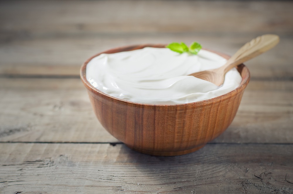 Greek yoghurt in wooden bowl on table