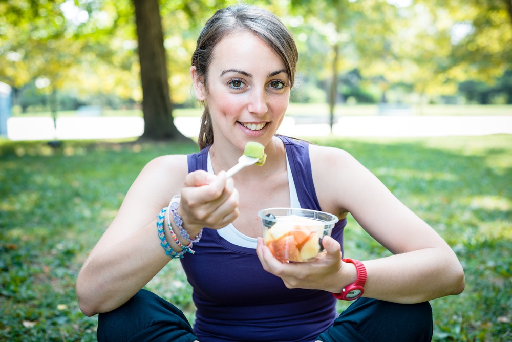 Woman eating fruit salad after running at the park